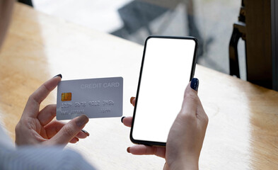 Online payment. woman holding smartphone with blank screen and credit card, making financial transaction