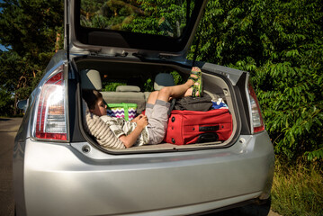 Cute little boy laying on the back of the bags and baggage in the car trunk ready to go on vacation...