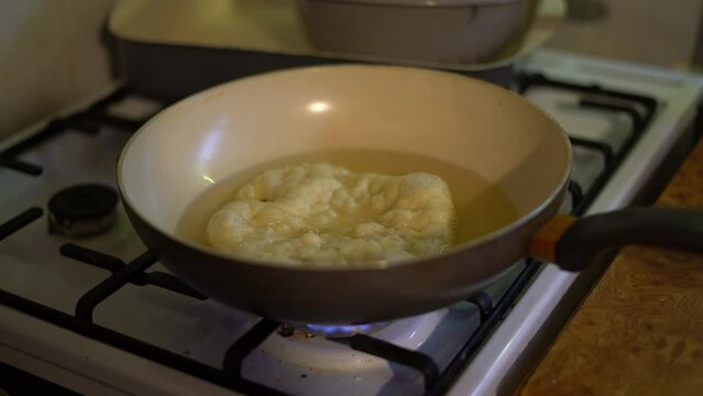 Langos frying in pan. Traditional Hungarian bread cooked at home