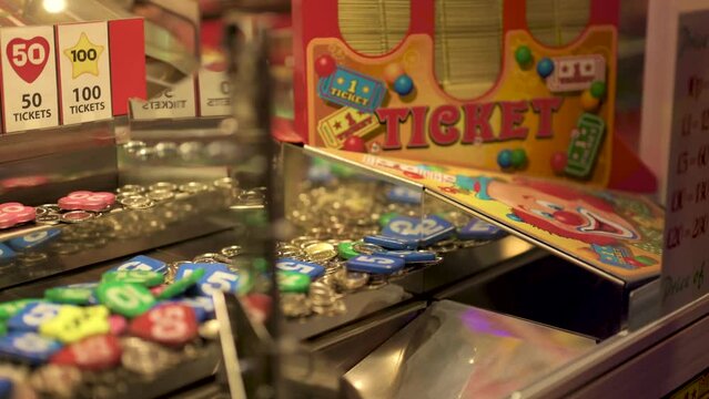 Arcade coin pusher dropping a 100 price, slow motion