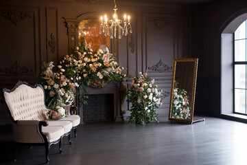 Black room interior with a vintage sofa, chandelier, mirror and fireplace decorated with flowers