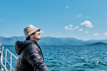 Mature asian man as tourist on boat trip. Chivyrkuisky Bay of Lake Baikal, Russia.
