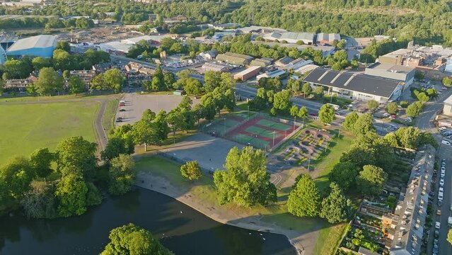Four outdoor tennis courts shaded by the green trees in Hillsborough Park of the local tennis club in Sheffield right on the English motorway A61. Drone lowering shot