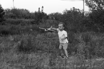 Monochrome photo. Little boy launches toy airplanes. Young aviator. The boy dreams of becoming an airplane pilot.