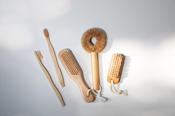 Eco brushes, for nails, washing dishes, toothbrushes with wooden handles on a white background with shadows. Top view