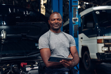 Portrait of man auto mechanic working at car repair shop with looking at camera.