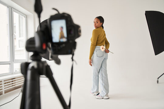 Multiracial professional model standing with camomile at the studio and posing to the camera