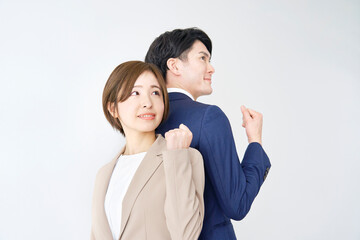 白背景に背中合わせでガッツポーズするビジネスウーマンとビジネスマン