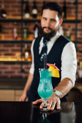 barman serving blue lagoon cocktail on bar counter