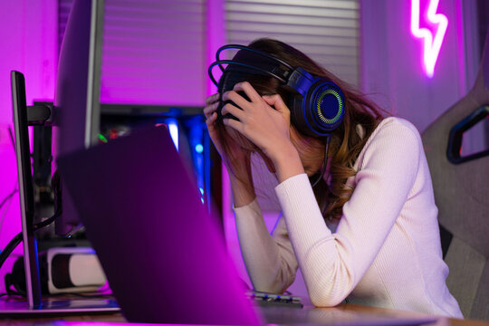 Game over loss match. Asian game with headphones playing online video game on computer PC neon light at home feeling sad disappointed about game losing, tournament player E-Sport - Powered by Adobe