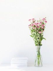 White book mockup with chrysanthemum flowers in a vase on a white table