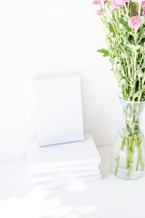 White book mockup with chrysanthemum flowers in a vase on a white table