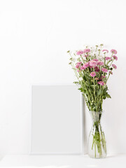 White frame mockup with chrysanthemum flowers in a vase on a white table