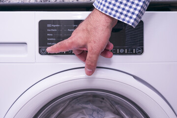 Mature man presses power button of washing machine.
