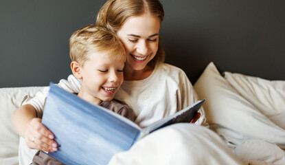 Happy mother and son reading book together on bed