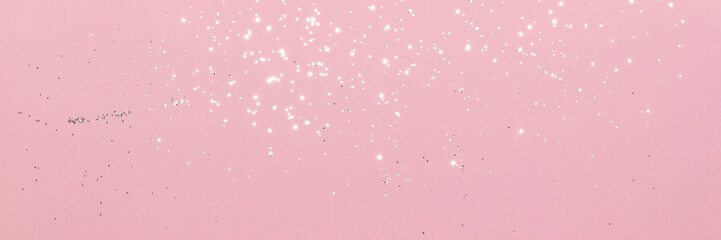 Sparkling silver glitter on pink background banner texture. Abstract holiday blurred lights header. Wide screen wallpaper. Panoramic web banner with copy space for design