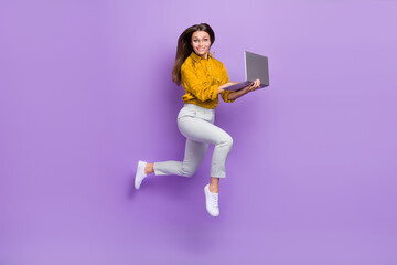 Full body photo of lovely lady jump write laptop wear blouse trousers sneakers isolated on violet color background