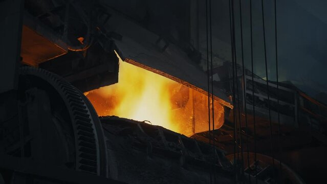 Bright flame in a metallurgical furnace. Close-up of the furnace. Sparks splatter. Many holding cables on the right. Metallurgical production process. 4K