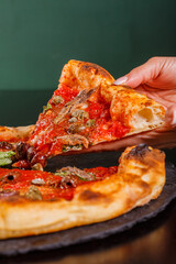 Pizza napoletana gourmet con sugo di pomodoro, basilico fresco, acciughe, olive nere e origano servita in una pizzeria napoletana