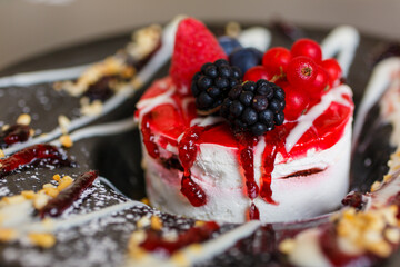 Cheesecake ai frutti di bosco servita come dolce in un elegante piatto nero decorato in un bar elegante 
