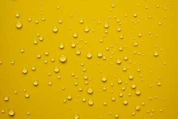 Lot of small drops on a yellow surface, splashed water. Abstract background. Top view. 