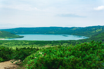 natural landscape of Kunashir island, view of the Golovnin volcano caldera with hot lakes and a path through the thickets of sasa and dwarf pines on a foreground