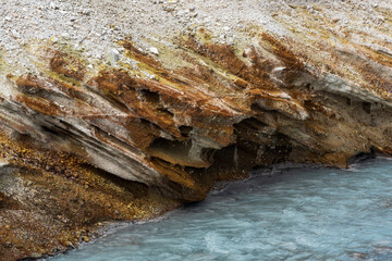 hydrothermal mineralised stream flowing on the slope of the volcano among the banks of volcanic ash and tephra