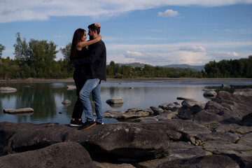 Fototapeta na wymiar couple in love hugging on the bank of the river. guy hugging a girl in nature