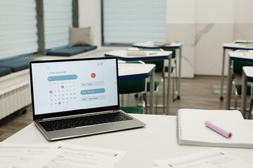 Horizontal image of workplace of teacher with laptop with organizer app on the screen in classroom
