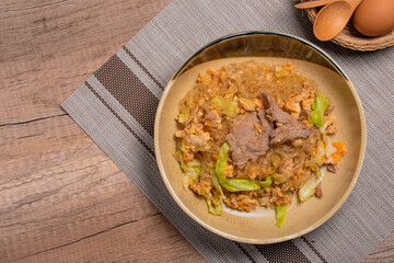 Stir fried vermicelli with pork, egg and collard greens in a white plate.