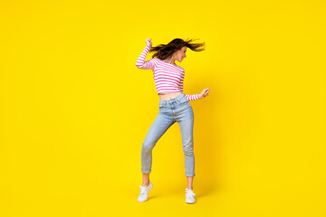 Fototapeta na wymiar Full size photo of pretty nice cute woman dressed striped shirt jeans white sneakers dancing have fun isolated on yellow color background