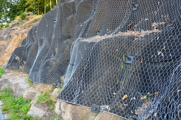 reinforcing slope with steel net anchored deep into rock. falling loose rock stones do not fall on...