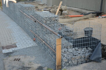 construction of a gabion retaining wall, as part of the house fencing. workers put geotextiles and...