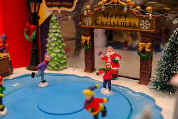 Obraz na płótnie Canvas Santa Claus in the snow across cute colorful houses and snowman. Christmas scene. Christmas decoration. Postcard