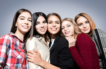 Fototapeta premium Beautiful portrait of happy girlfriends on grey background.