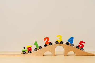 Colorful toy train locomotive with numbers on wooden railway on beige background. Educational game....