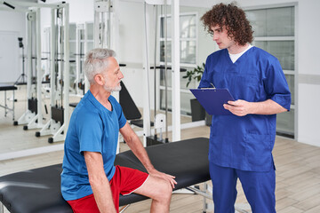 Male manual therapist telling prescriptions to his male patient at rehabilitation centre