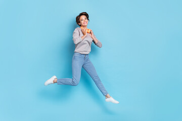 Fototapeta na wymiar Full size photo of short hairdo millennial lady jump wear headphones shirt jeans sneakers isolated on blue color background