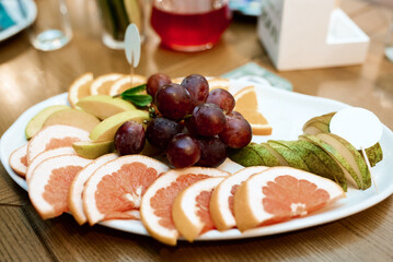 Fresh fruits in platdifferent fresh fruits on a white plate on a wooden tablee with cutting board on wooden table