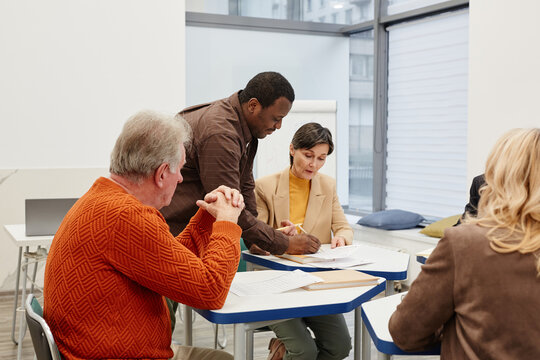 African teacher talking to students during lesson, he explaining them new material while they sitting at desks in classroom