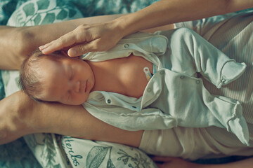 A newborn baby is lying on his mother's lap