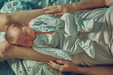 A newborn baby is lying on his mother's lap