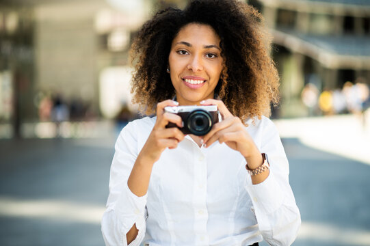 portrait of happyblack woman taking photos with a mirrorless camera
