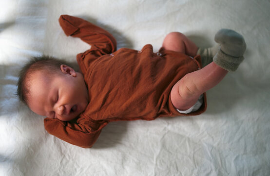 A Newborn Baby Yawns In His Crib From Above