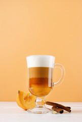 bright pumpkin spice latte in a glass mug with cinnamon