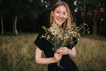 beautiful young girl in black dress and with long hair is resting in nature