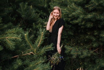 beautiful young girl in black dress and with long hair is resting in nature