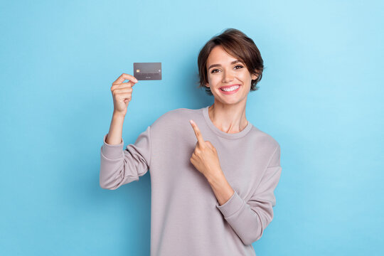 Photo of satisfied girl bob hairstyle dressed gray pullover directing credit card internet purchase isolated on blue color background