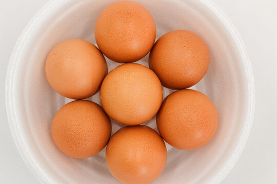 Seven Raw Chicken Eggs In A Styrofoam Cup With White Background.