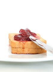Homemade strawberry jam above toast bread with plate and breakfast knife. Breakfast concept. Selective focus. Copy space area.